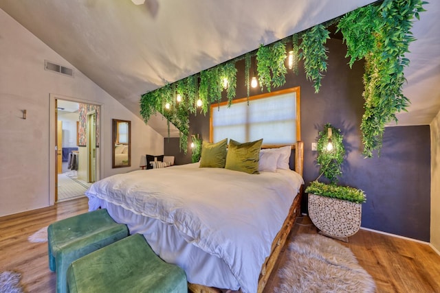 bedroom featuring hardwood / wood-style floors, ensuite bathroom, and vaulted ceiling