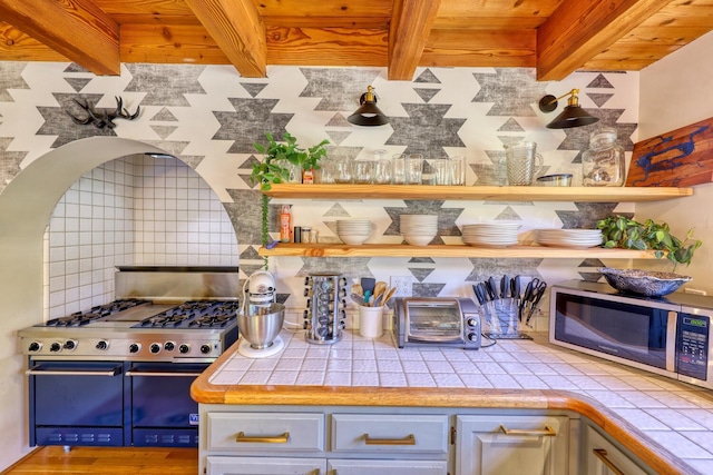 kitchen with tile countertops, wooden ceiling, backsplash, beamed ceiling, and stainless steel appliances