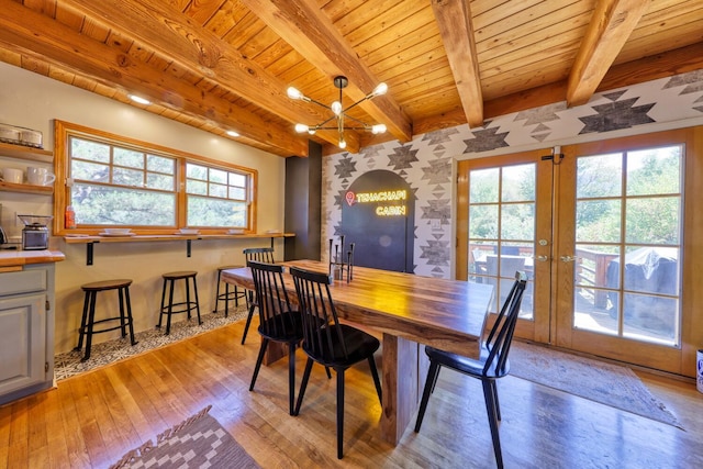 dining area with french doors, beamed ceiling, a chandelier, wood ceiling, and light wood-type flooring