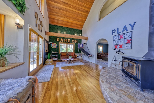 living room with hardwood / wood-style flooring, a wood stove, high vaulted ceiling, and french doors