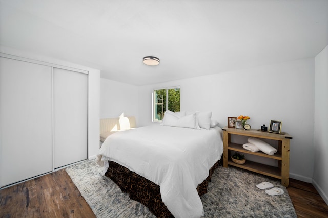 bedroom featuring dark wood-style flooring, a closet, and baseboards
