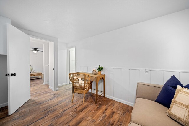 living area with dark wood-style floors and a wainscoted wall