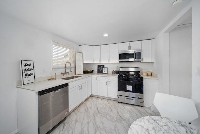 kitchen with appliances with stainless steel finishes, white cabinets, light countertops, and a sink
