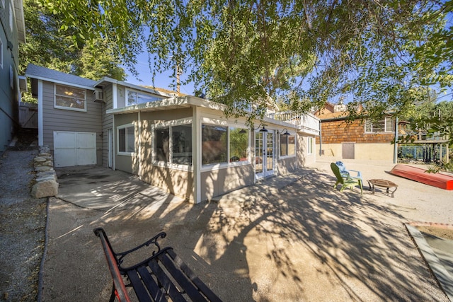 rear view of property with a shingled roof, a patio area, and a fire pit