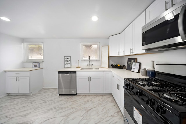 kitchen with stainless steel appliances, light countertops, a sink, and white cabinetry