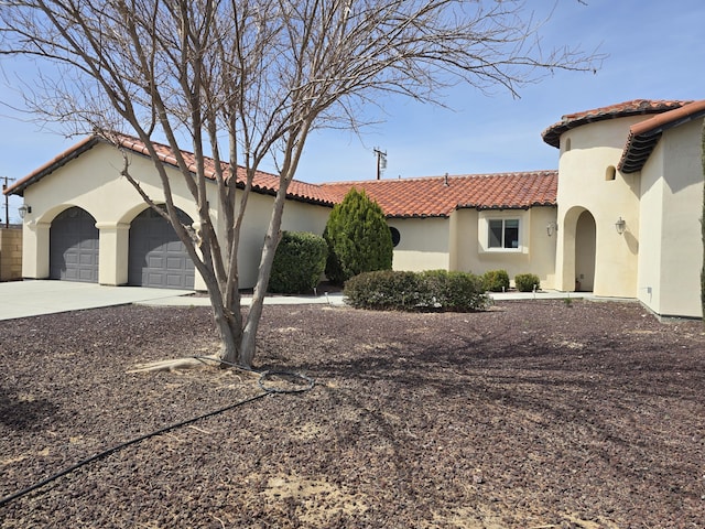 view of front facade featuring a tiled roof, an attached garage, concrete driveway, and stucco siding