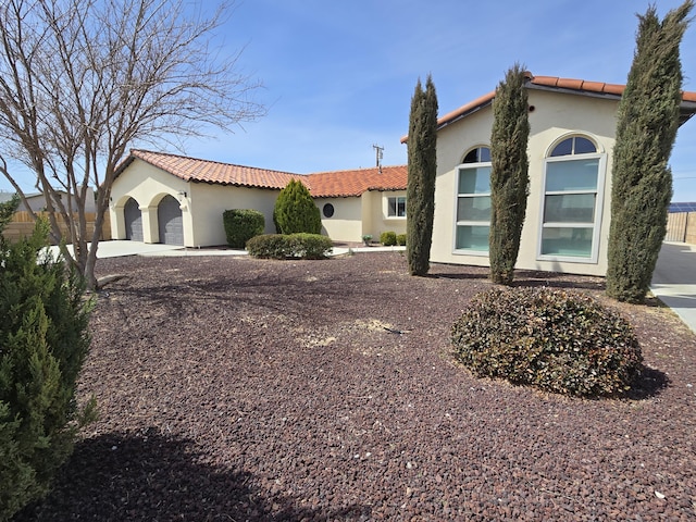 view of front of property featuring a garage, stucco siding, a tiled roof, and concrete driveway