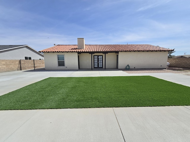 mediterranean / spanish home with french doors, fence, a patio area, and a front lawn