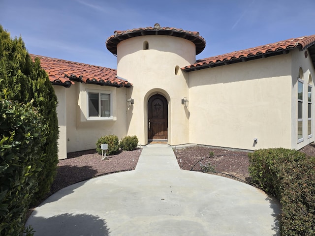 view of front facade featuring a tile roof, a patio area, and stucco siding