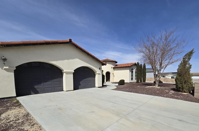 view of front of house with a tiled roof, an attached garage, driveway, and stucco siding