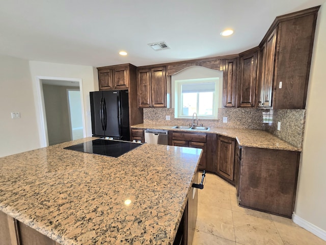 kitchen featuring dark brown cabinetry, visible vents, tasteful backsplash, a sink, and black appliances