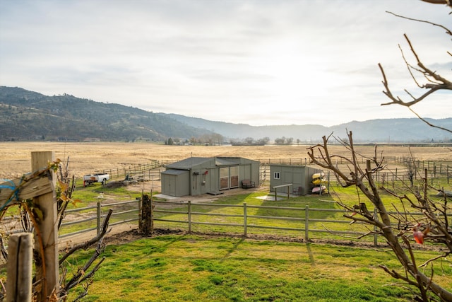 view of yard with a mountain view, an outbuilding, and a rural view