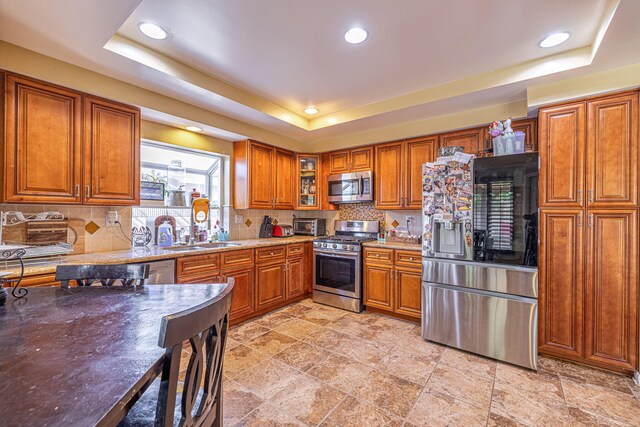 kitchen featuring tasteful backsplash, stainless steel appliances, and a tray ceiling