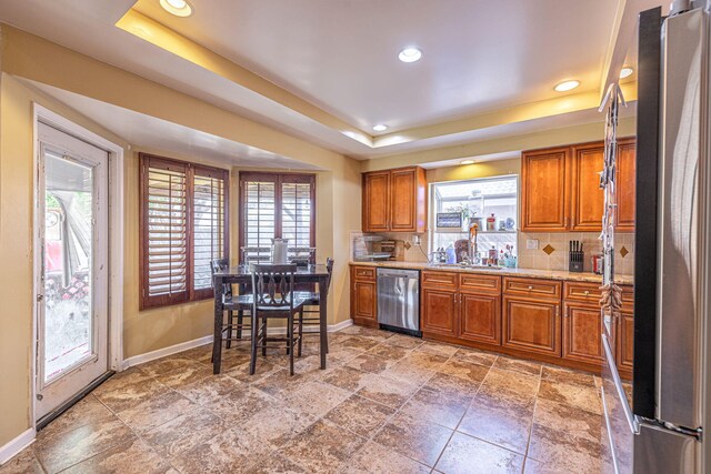 kitchen with stainless steel appliances, tasteful backsplash, a tray ceiling, and sink