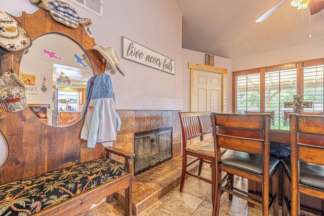 living area featuring a tiled fireplace and ceiling fan