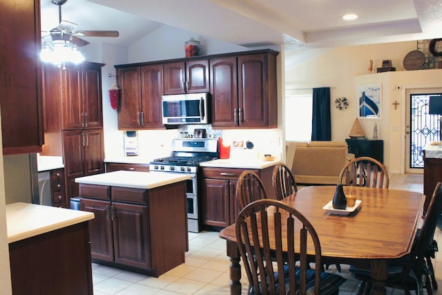 kitchen with ceiling fan, stainless steel appliances, light tile patterned flooring, vaulted ceiling, and a center island