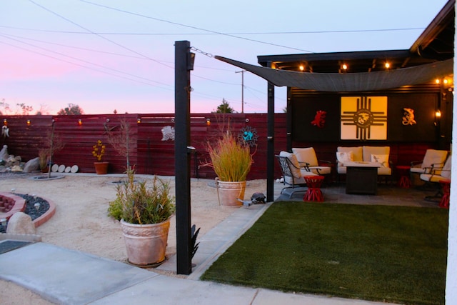 patio terrace at dusk featuring a lawn