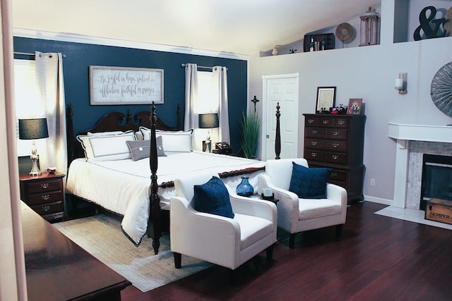 bedroom with dark wood-type flooring, lofted ceiling, and a fireplace