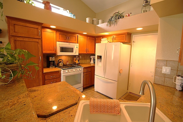 kitchen featuring white appliances, light tile patterned floors, brown cabinets, and backsplash