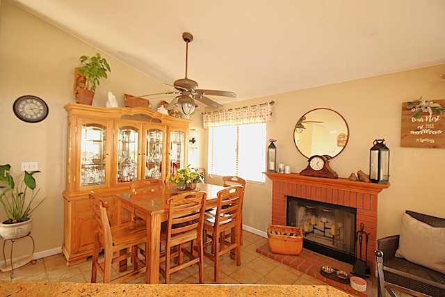 dining space with a brick fireplace, baseboards, ceiling fan, lofted ceiling, and light tile patterned floors