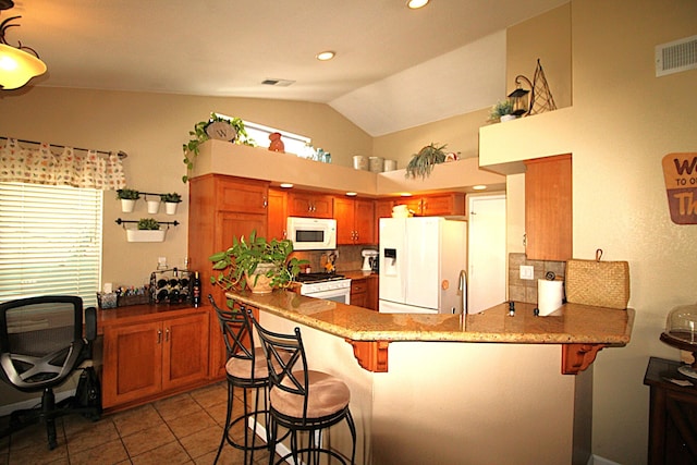 kitchen with visible vents, a kitchen bar, white appliances, a peninsula, and decorative backsplash