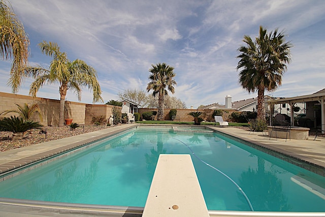 view of swimming pool with a patio area, a pool with connected hot tub, a fenced backyard, and a diving board