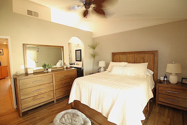 bedroom featuring visible vents, lofted ceiling, dark wood-type flooring, and arched walkways