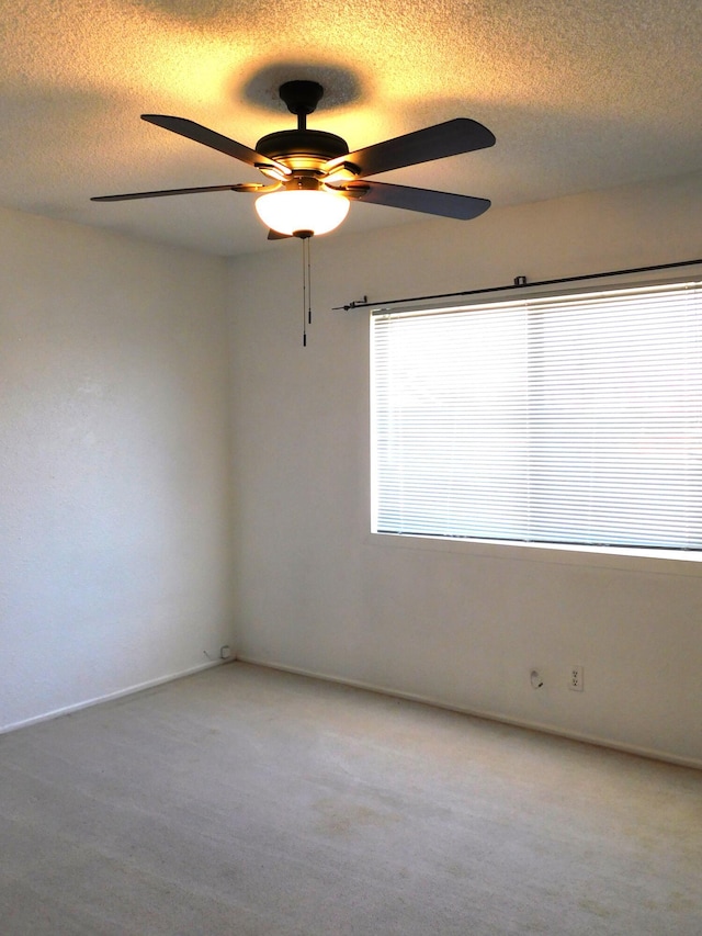 carpeted empty room featuring ceiling fan and a textured ceiling