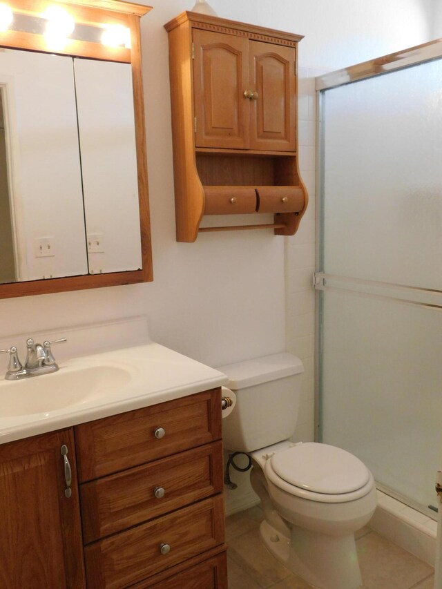 bathroom featuring tile patterned flooring, vanity, toilet, and an enclosed shower