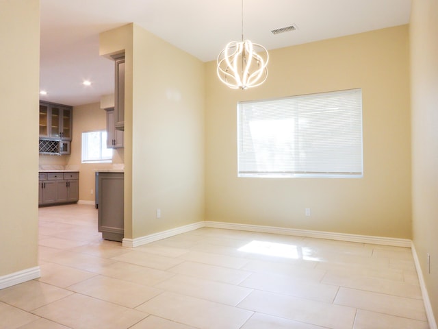 spare room featuring a notable chandelier and light tile patterned flooring