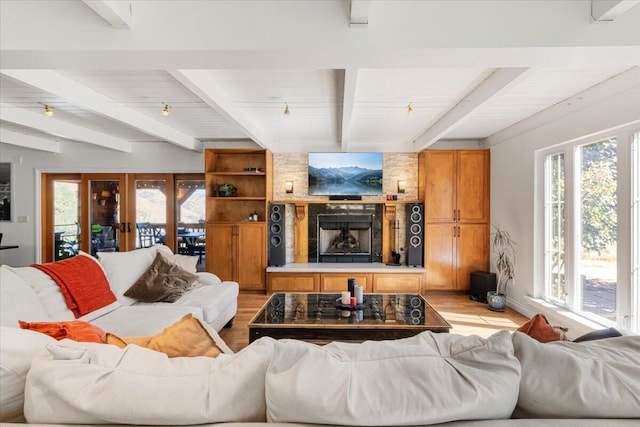 living room featuring beamed ceiling, light wood-type flooring, and plenty of natural light