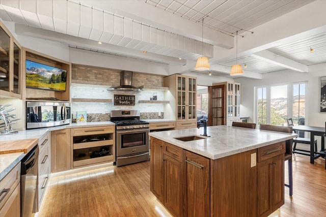 kitchen featuring pendant lighting, sink, wall chimney exhaust hood, appliances with stainless steel finishes, and beam ceiling