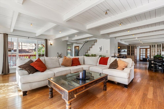 living room featuring beamed ceiling and light hardwood / wood-style flooring