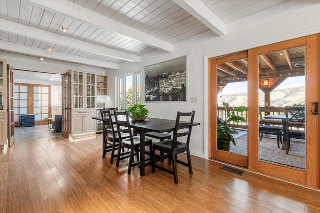 dining space featuring a mountain view, french doors, light hardwood / wood-style flooring, and beamed ceiling