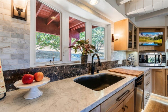 kitchen with light brown cabinets, sink, appliances with stainless steel finishes, beam ceiling, and light stone counters