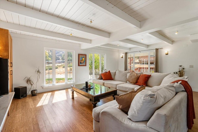 living room featuring beamed ceiling and light hardwood / wood-style floors