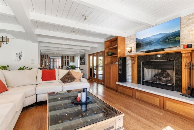 living room with a fireplace, beam ceiling, hardwood / wood-style flooring, and french doors