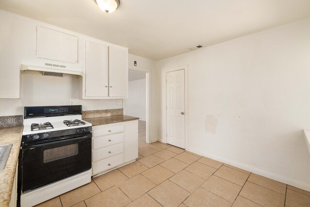 kitchen with white gas stove, white cabinets, and light tile patterned floors