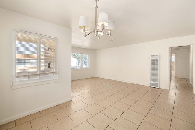 tiled spare room featuring a chandelier