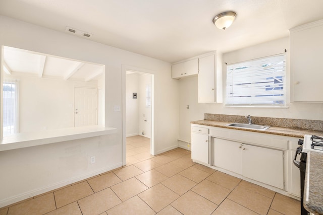 kitchen with white cabinetry, sink, light tile patterned floors, and electric range oven