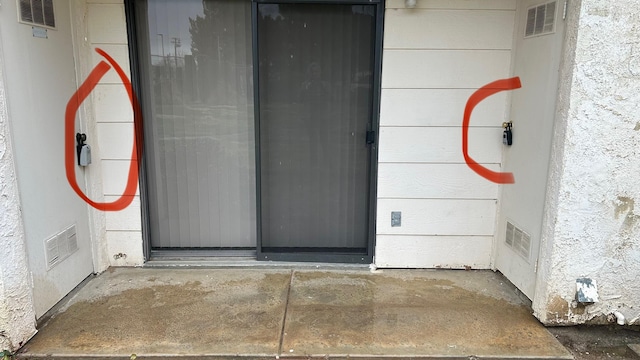 property entrance featuring visible vents and stucco siding