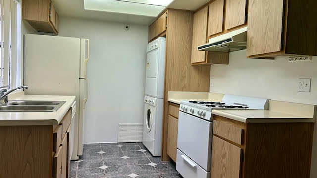 kitchen with stacked washer and dryer, white range with gas stovetop, visible vents, light countertops, and under cabinet range hood