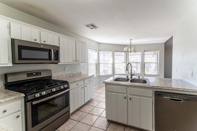 kitchen featuring white cabinetry, sink, stainless steel appliances, and decorative light fixtures