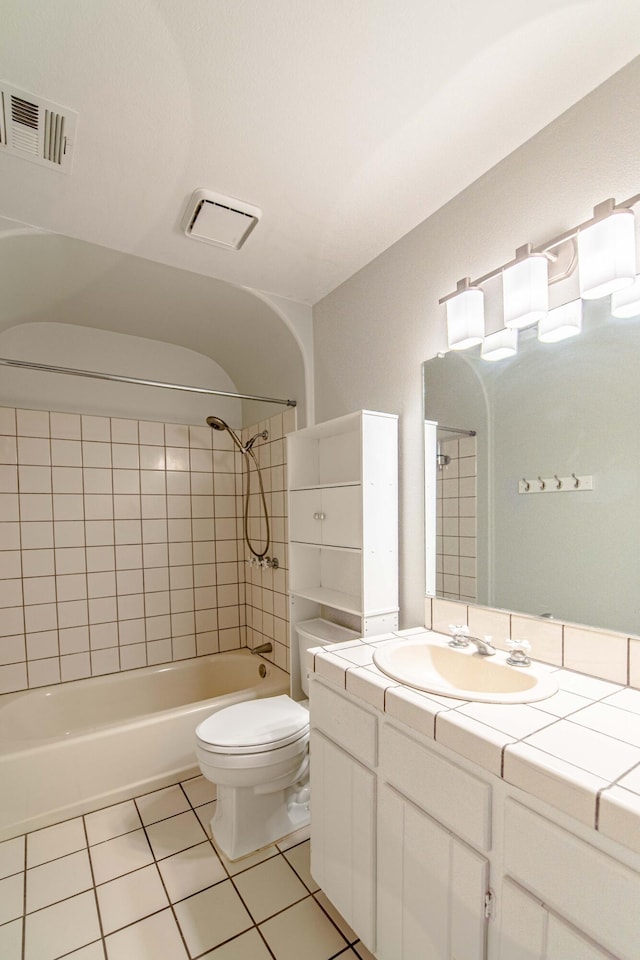 full bathroom featuring tile patterned floors, tiled shower / bath combo, toilet, and vanity