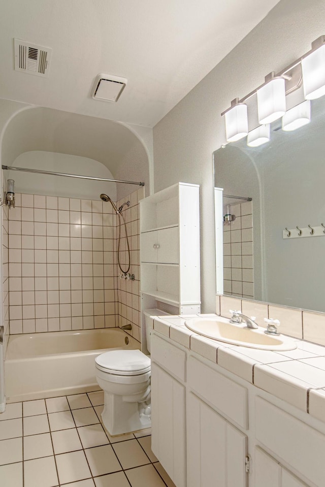 full bathroom featuring tile patterned flooring, tiled shower / bath combo, toilet, and vanity