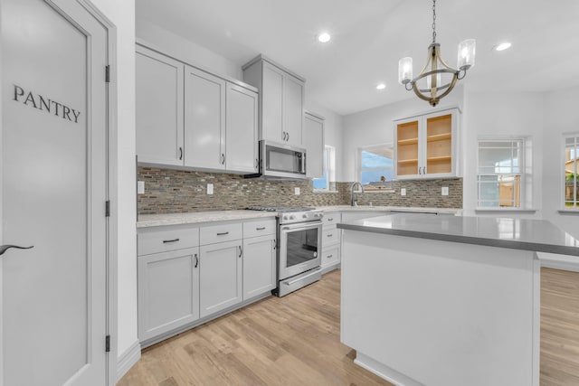 kitchen with appliances with stainless steel finishes, an inviting chandelier, a kitchen island, and tasteful backsplash