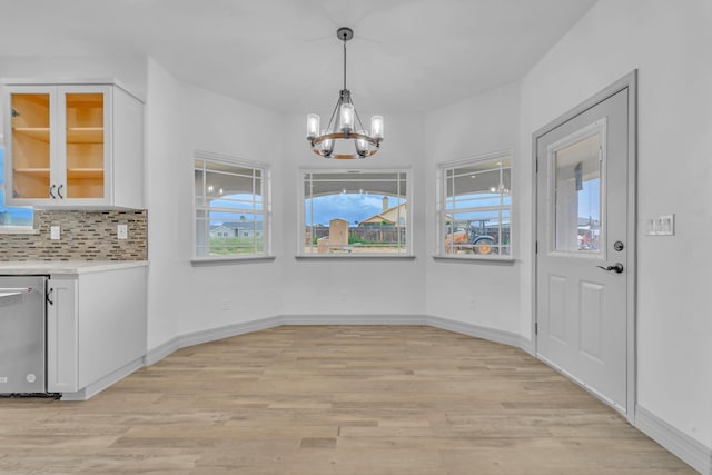 unfurnished dining area with a notable chandelier and light wood-type flooring