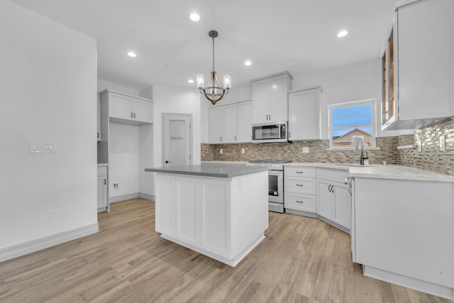 kitchen with pendant lighting, a center island, an inviting chandelier, white cabinetry, and stainless steel appliances