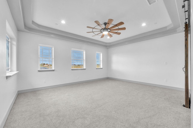 carpeted empty room with a tray ceiling and ceiling fan