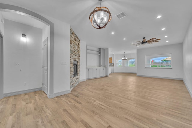 unfurnished living room with a fireplace, ceiling fan with notable chandelier, and light wood-type flooring